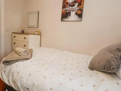 a bedroom with a bed with a dresser and amitted at 2 Mountain View in Wrexham