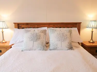 a bed with white sheets and pillows with two lamps at Dwynant in Dolgellau
