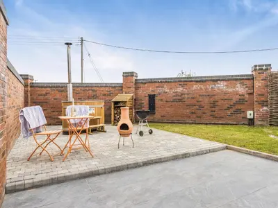 a patio with chairs and a table and a brick building at The Little House - Uk49129 in Stapleton
