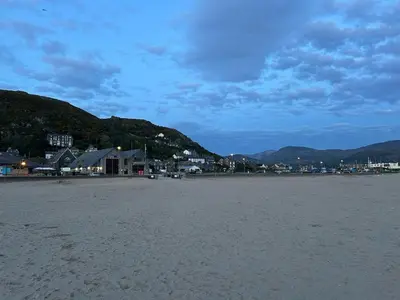 a beach with a town and mountains in the background at The Cottage on the Rock in Barmouth