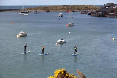 three people on surfboards in the water with boats at 3 Bed in Dolgellau oc-h31822 in Dolgellau