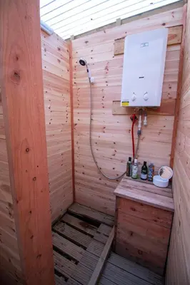 a sauna with a shower in a wooden wall at The Charcoal Hut woodland retreat in Llandovery