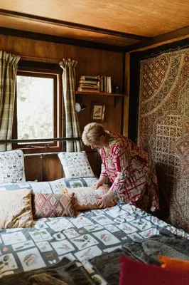 a woman is standing next to a bed at The Charcoal Hut woodland retreat in Llandovery