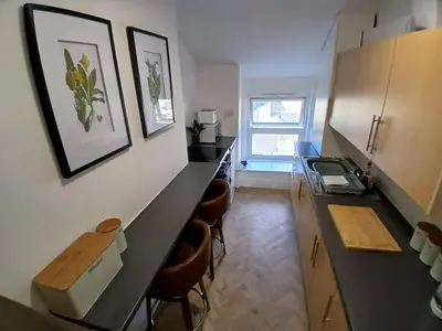 a kitchen with a black counter and stools in it at Seashell Apartment in Barmouth