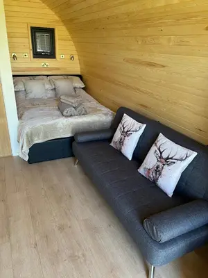 a living room with a couch and a bed at Mynd View Pods Cedar in Craven Arms