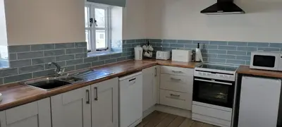 a kitchen with white cabinets and a sink at Dog friendly rural location in Llanerch-Aeron