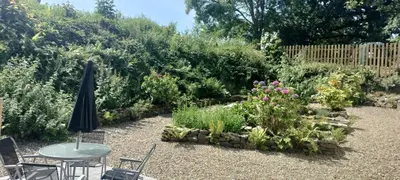 a garden with a table and chairs and flowers at Dog friendly rural location in Llanerch-Aeron