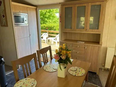 a dining room table with a vase of flowers on it at The Panorama View Luxury Retreat in Aberystwyth in Aberystwyth