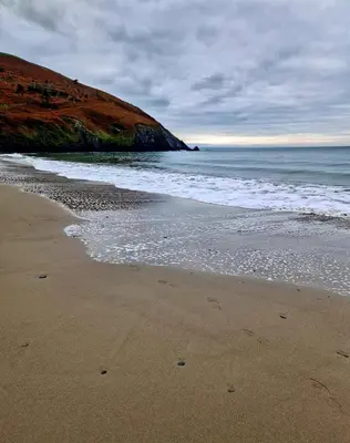 a sandy beach with the ocean and a hill at River View Modern 3 Bedroom Pet Friendly in Clarach Bay in Aberystwyth