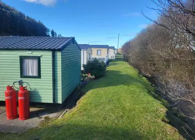 a green house with two red fire hydrants next to a yard at River View Modern 3 Bedroom Pet Friendly in Clarach Bay in Aberystwyth