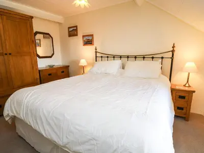 a bedroom with a large white bed with two lamps at Tyn Y Graig in Arthog