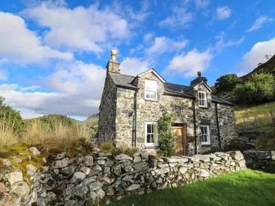 an old stone house with a stone wall at Tyn Y Graig in Arthog