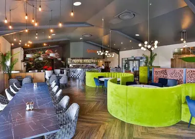 a restaurant with green chairs and tables and a bar at Meadow Springs Country & Leisure Park in Caersws