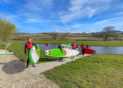 a group of people holding surfboards on a path at Meadow Springs Country & Leisure Park in Caersws