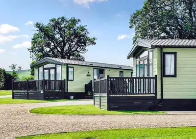 a small green house with a fence in front of it at Meadow Springs Country & Leisure Park in Caersws