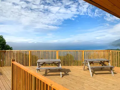 two benches sitting on a wooden deck with the ocean at Bron-Yr-Aur - Uk49616 in New Quay