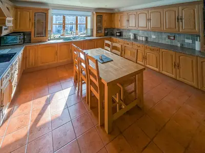 a large kitchen with wooden cabinets and a wooden table at Bron-Yr-Aur - Uk49616 in New Quay