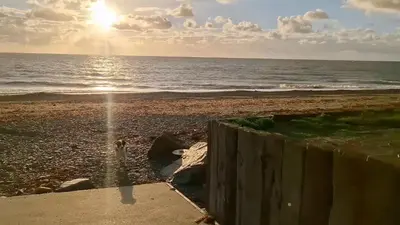 a beach with the sun rising over the ocean at Awel Mor Beautiful Pet Friendly Chalet in Clarach Bay in Aberystwyth