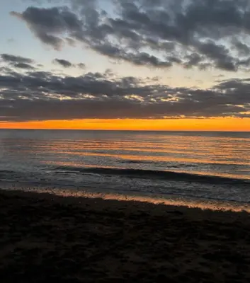 a view of the ocean at sunset at Awel Mor Beautiful Pet Friendly Chalet in Clarach Bay in Aberystwyth