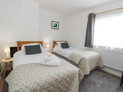 two beds in a room with a window and a bedskirts at Brycheiniog View in Brecon