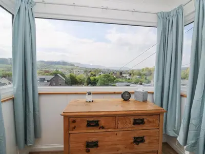 a window with blue curtains and a wooden dresser at Brycheiniog View in Brecon