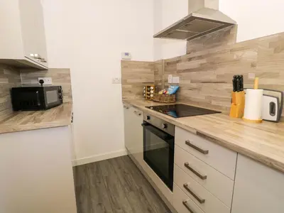 a kitchen with white cabinets and a black stove top oven at Gilfach Bach in Dolgellau