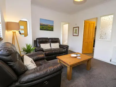 a living room with a leather couch and a coffee table at Gilfach Bach in Dolgellau