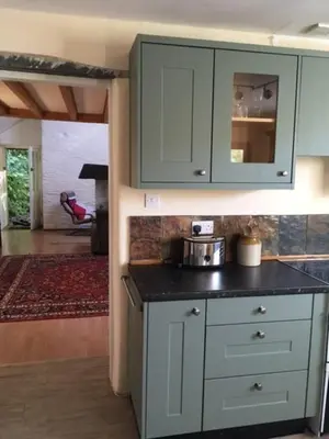 a kitchen with green cabinets and a counter top at Pretty sunny cottage, Machynlleth in Machynlleth