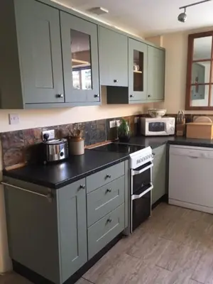 a kitchen with white cabinets and a black counter top at Pretty sunny cottage, Machynlleth in Machynlleth