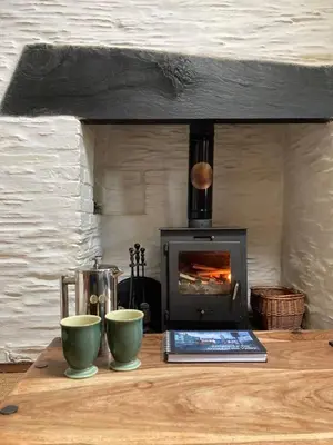 a stove sitting on a wooden table with two cups at Pretty sunny cottage, Machynlleth in Machynlleth