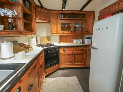 a kitchen with wooden cabinets and a white refrigerator at Penygrisiau in Barmouth