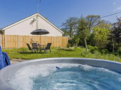 a hot tub in a yard with a table and chairs at 2 Bed in Llanon oc-96072 in Pennant