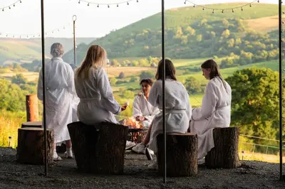 a group of people in white robes sitting around a grill at Oolert Treehouse in Hundred House