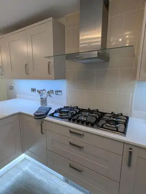 a kitchen with white cabinets and a stove top oven at Bwthyn Y Mor in Llanddwywe