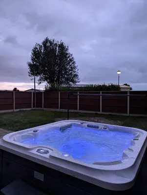 a jacuzzi tub with blue water in a yard at Bwthyn Y Mor in Llanddwywe