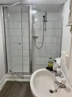 a bathroom with a shower and a white sink at Oaklands Farm in Preesgreen