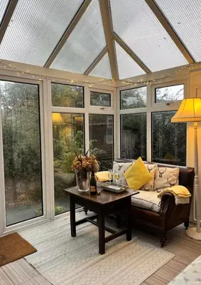 a conservatory with a couch and a table and windows at Oaklands Farm in Preesgreen