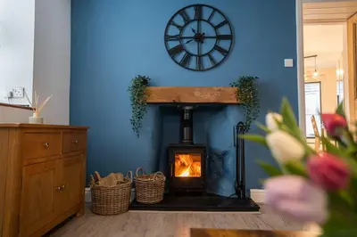 a fireplace in a blue room with a clock on the wall at Cosy townhouse with log burner in Dolgellau