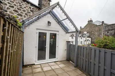 a small white house with a gate and a fence at Cosy townhouse with log burner in Dolgellau