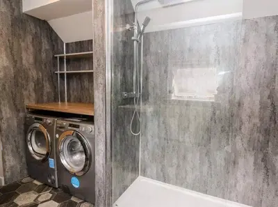 a shower in a bathroom with a washing machine at Beautiful cottage with log burner in Dolgellau