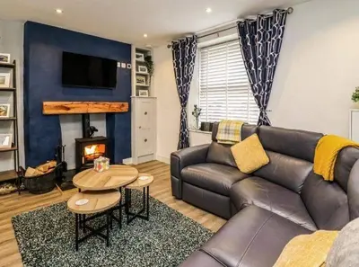 a living room with a leather couch and a fireplace at Beautiful cottage with log burner in Dolgellau