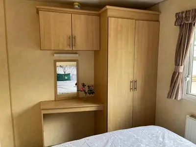 a bedroom with wooden cabinets and a bed and a window at Sylvan Near Hay on Wye in Rhos-gôch