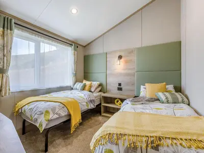 a bedroom with two beds and a window at Hillfort Lodge in Llanrhystyd