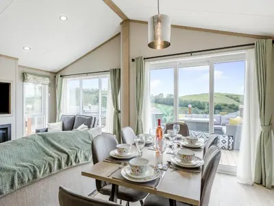 a dining room with a table and chairs and a couch at Hillfort Lodge in Llanrhystyd
