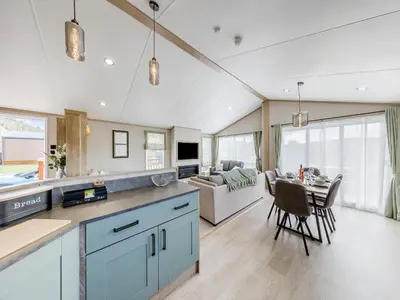 a kitchen and living room with a table and a couch at Hillfort Lodge in Llanrhystyd