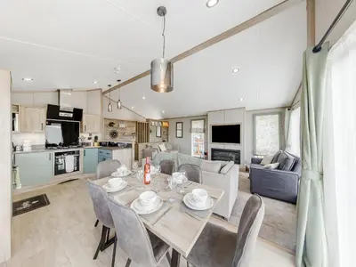 a dining room and living room with a table and chairs at Hillfort Lodge in Llanrhystyd