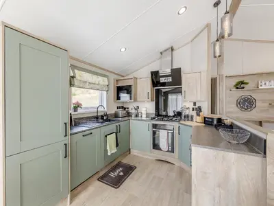 a kitchen with green cabinets and wooden floors at Hillfort Lodge in Llanrhystyd