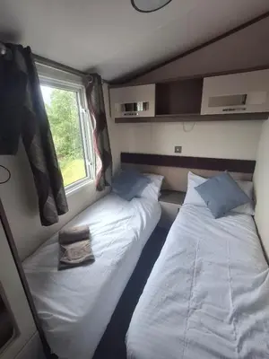 two beds in a small room with a window at 'Falcons Rest' in Borth