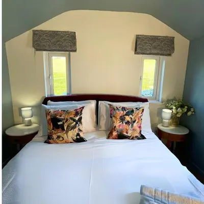 a bedroom with a bed with white sheets and two windows at Gwyneska in Llanaber