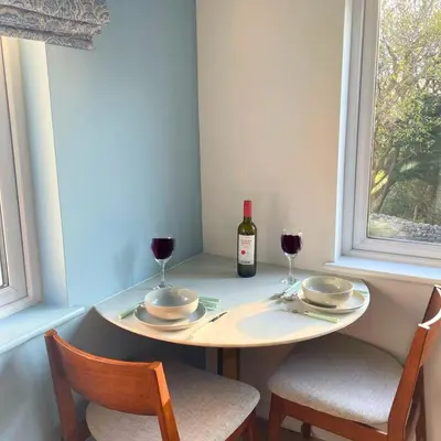 a table with a bottle of wine and two chairs at Gwyneska in Llanaber
